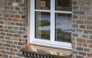 Holzfenster in weiß Weißes Holzfenster mit Sprossen und Fensterbank aus Kupfer