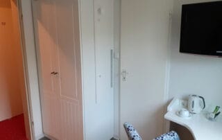 Kleiderschrank mit profilierten Türen und Lüftungsschlitzen für den Einbau einer Minibar, Hotel Mingers, Neuharlingersiel