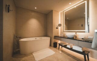 Waschtisch und Sitzbank im Badezimmer mit beleuchtetem Spiegel Waschtisch und Sitzbank im Badezimmer mit beleuchtetem Spiegel
