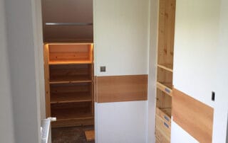 Begehbarer Kleiderschrank in weiß mit Schiebetüren und akzentuiertem Holzfurnier Begehbarer Kleiderschrank in weiß mit Schiebetüren und akzentuiertem Holzfurnier