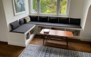 Sitzecke in weiß mit Polsterung und Bücherregal im Fußraum